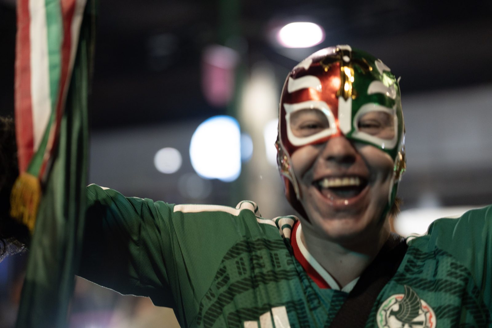 A fan in a tricolor luchador mask laughing