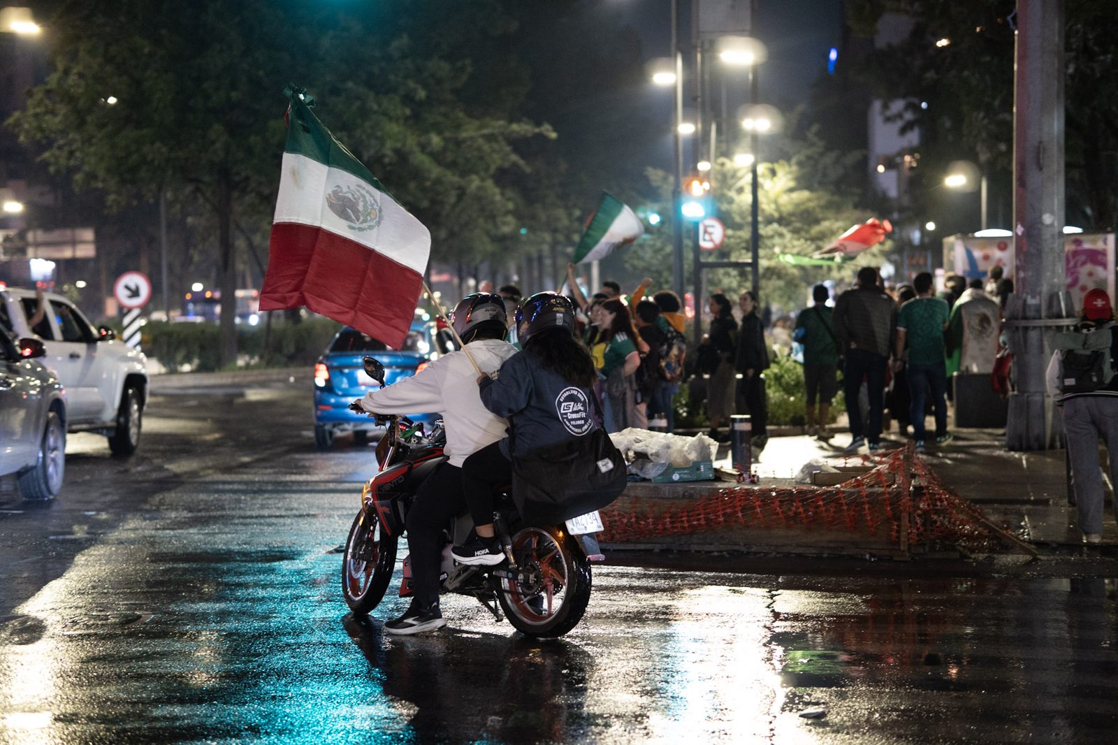 A couple riding through the celebration with a full-size Mexican flag